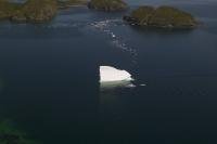 Aerial photo of an iceberg floating between islands off the Newfoundland coastline.