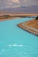 The aqua colored water of the Pukaki Canal flowing towards Lake Benmore in Canterbury on the South Island of New Zealand.