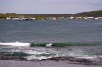 The water laps up along the coastline with the village of Raleigh in Ha Ha Bay in Newfoundland Labrador in Canada perched on the opposite side.