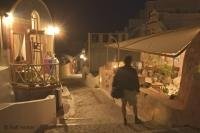 A tourist finishing up his day in Oia, Santorini by doing some late night shopping.