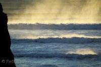The wisps of seapray are lit up by the setting sun at Oceanside Beach in Oregon, USA.