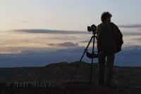 The silhouette of famous photographer Rolf Hicker on a photo assignment taking a picture in Dinosaur Provincial Park, Alberta, Canada.