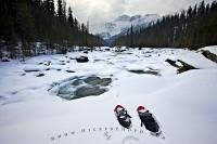 As clouds descend, beginning to cover the peak of Mount Sarbach in Banff National Park, snowshoes are abandoned in the winter snow on the banks of the Mistaya River in the Rocky Mountains.