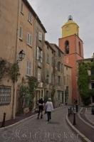 The colourful bell tower of the Eglise Notre Dame can be seen at the end of the the Rue Saint Jean, which is a narrow winding street in the Old Town of St Tropez in The Var, a department in the beautiful Provence, France.
