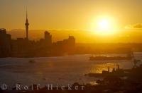 Brillant yellow fills the sky as the sun hangs above the Waitemata Harbour and central business district in the city of Auckland, New Zealand's largest metropolitan situated on the North Island.