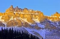 The jagged peaks of the mountain, aptly named Dolomite Peak, rise up to 2,782 metres and are part of the Canadian Rocky Mountains in Banff National Park. The sunlit peaks glow as the sun sets for another day.