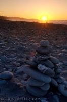 A rock memorial stands in the glowing rays of the disappearing sunset on Gillespies Beach near Fox Glacier in New Zealand.