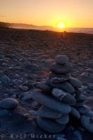 A rock memorial stands in the glowing rays of the disappearing sunset on Gillespies Beach near Fox Glacier in New Zealand.