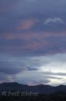 The hills are silhouetted as the reflection of sunset tints the clouds above near Keeler in California, USA.