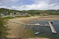 The wide, sandy beach in the village of Tadoussac in Quebec, Canada forms a semi-circle around the water's edge and the marina.