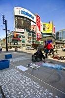 A man creates an artwork picture in chalk on the street in Yonge-Dundas Square in the downtown core of Toronto, Ontario in Canada.