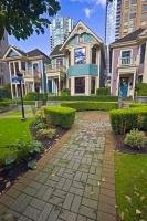A row of historic Victorian style houses are surrounded by the high rise buildings of downtown Vancouver, British Columbia, Canada.