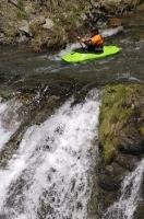 A kayaking enthusiast paddles up to the brink of the waterfall in the Pyrenees, Catalonia, Spain.