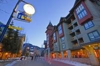 A picture of the plaza of Whistler Village in winter as people walk along the Village Stroll at dusk.