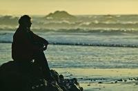 The silhouette of a woman sitting on a rock on Ruby Beach in the Olympic National Park, Olympic Peninsula of Washington, USA.