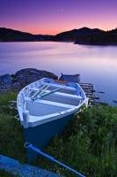 A wooden fishing boat resting on the shore at twilight in the small town of Fleur de Lys in Newfoundland, Canada is a peaceful sight.